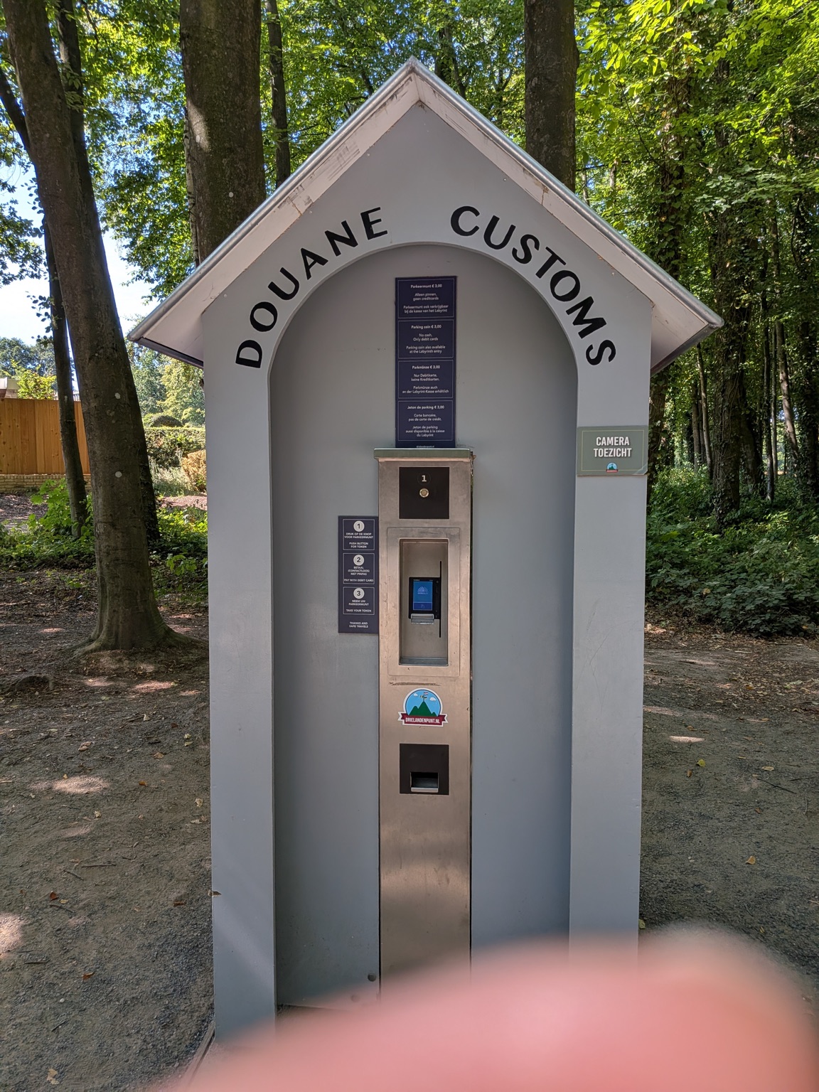 A payment booth styled as a customs house, labelled Douane Customs, at the entrance to the Drielandenpunt car park